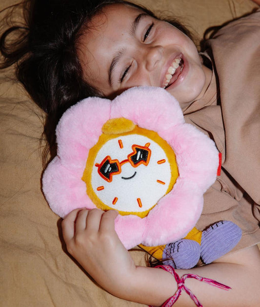 Fille allongée tenant la peluche en forme d'horloge-fleur Tic Tac Bloom contre elle - photo lifestyle - Hello Hossy