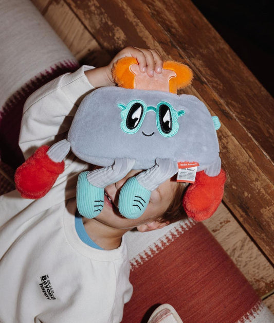 Garçon debout tenant devant son visage la peluche originale Punchy Toast - vue de face - Hello Hossy
