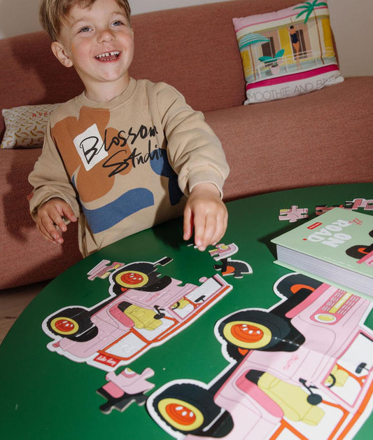 Garçon assemblant le puzzle coloré 24 pièces "On The Road" sur une table – ambiance ludique – Hello Hossy